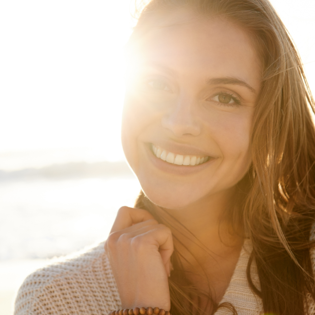 Woman smiling to camera with sun shining on half her face